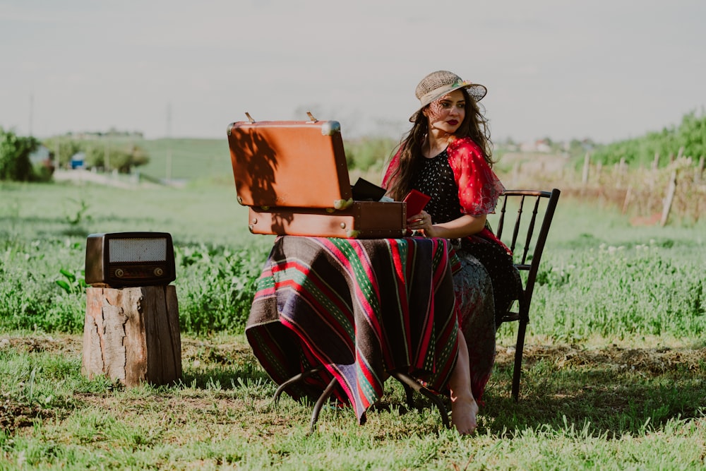 woman sitting near table in green field