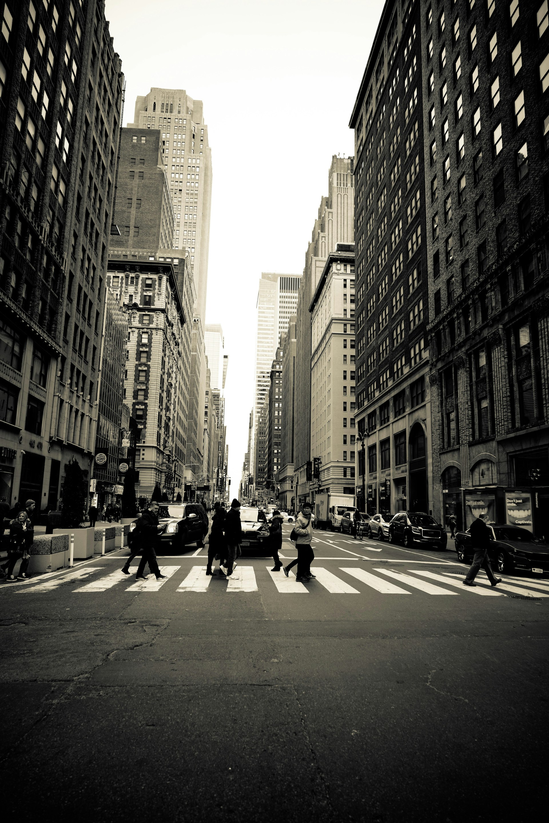 people crossing at pedestrian lane in between buildings