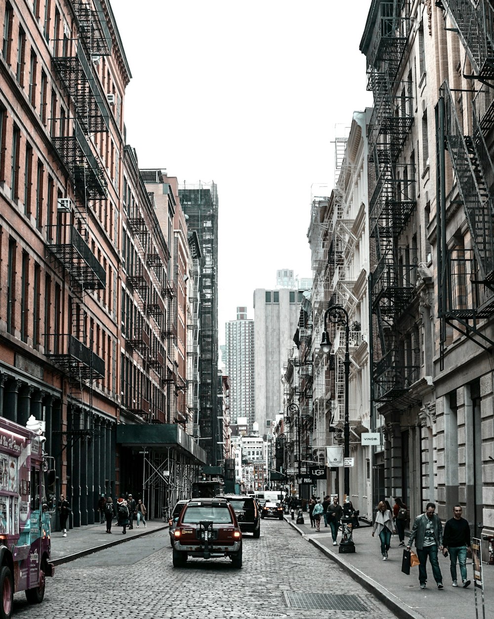 vehicle on road between walking people and buildings