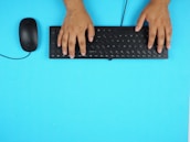 Close-up of hands typing on a keyboard with a clean, bright office background.