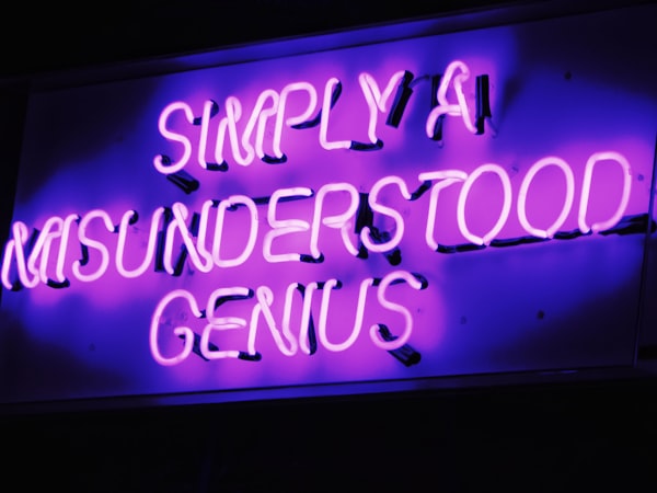 a neon sign reading "simply a misunderstood genius"