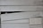 The image displays a section of overlapping wooden siding planks. The planks have a horizontal orientation and feature a weathered, aged texture with visible wood grain. There is a noticeable broken or misaligned plank in the middle, creating an uneven appearance.