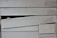 The image displays a section of overlapping wooden siding planks. The planks have a horizontal orientation and feature a weathered, aged texture with visible wood grain. There is a noticeable broken or misaligned plank in the middle, creating an uneven appearance.