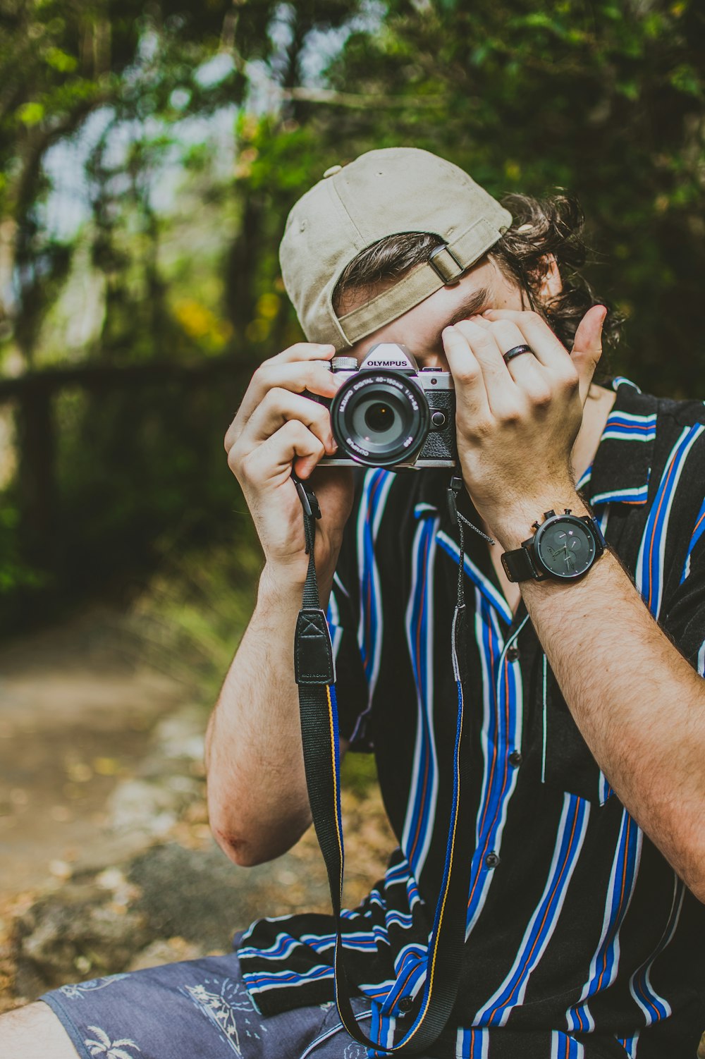 man wearing blue and black striped shirt holding camera taking a picture