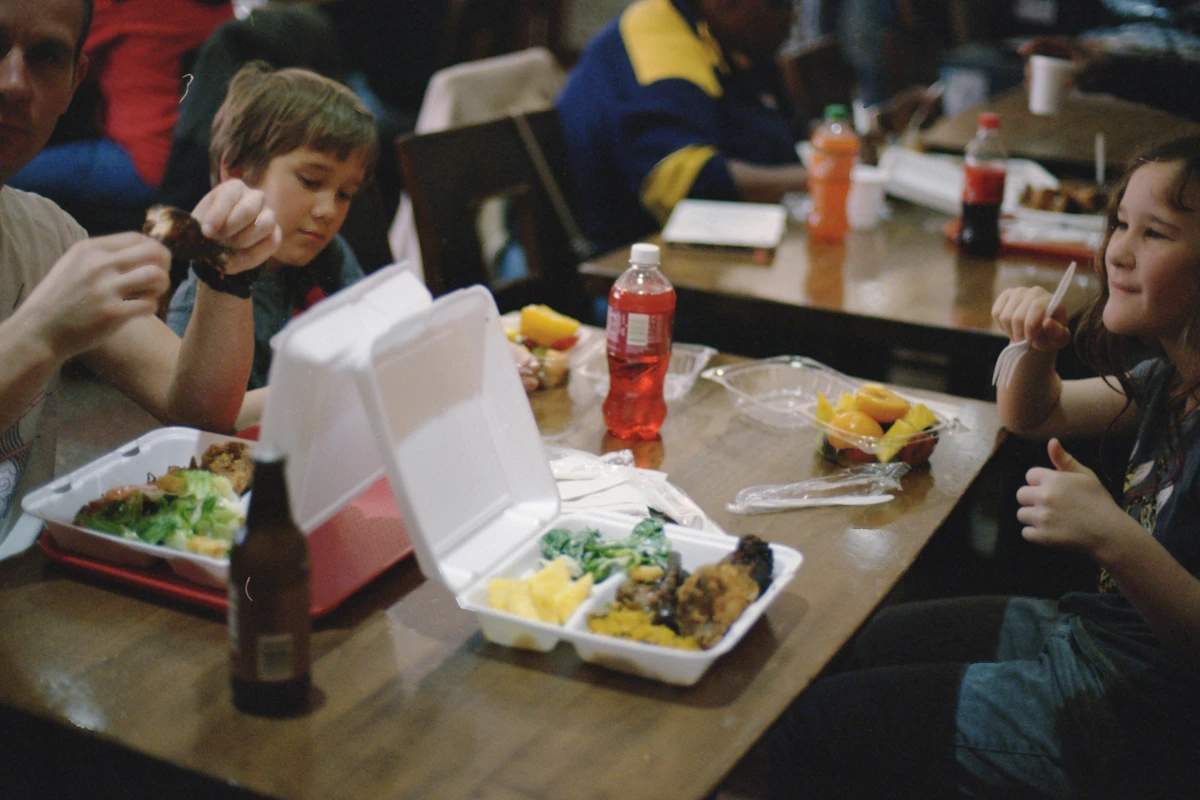 Two school-age children eating a meal together at a dining table, illustrating everyday routines that support children's digestive health
