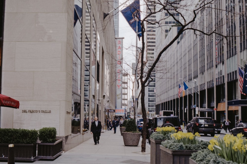 man wearing suit jacket walking beside buildings