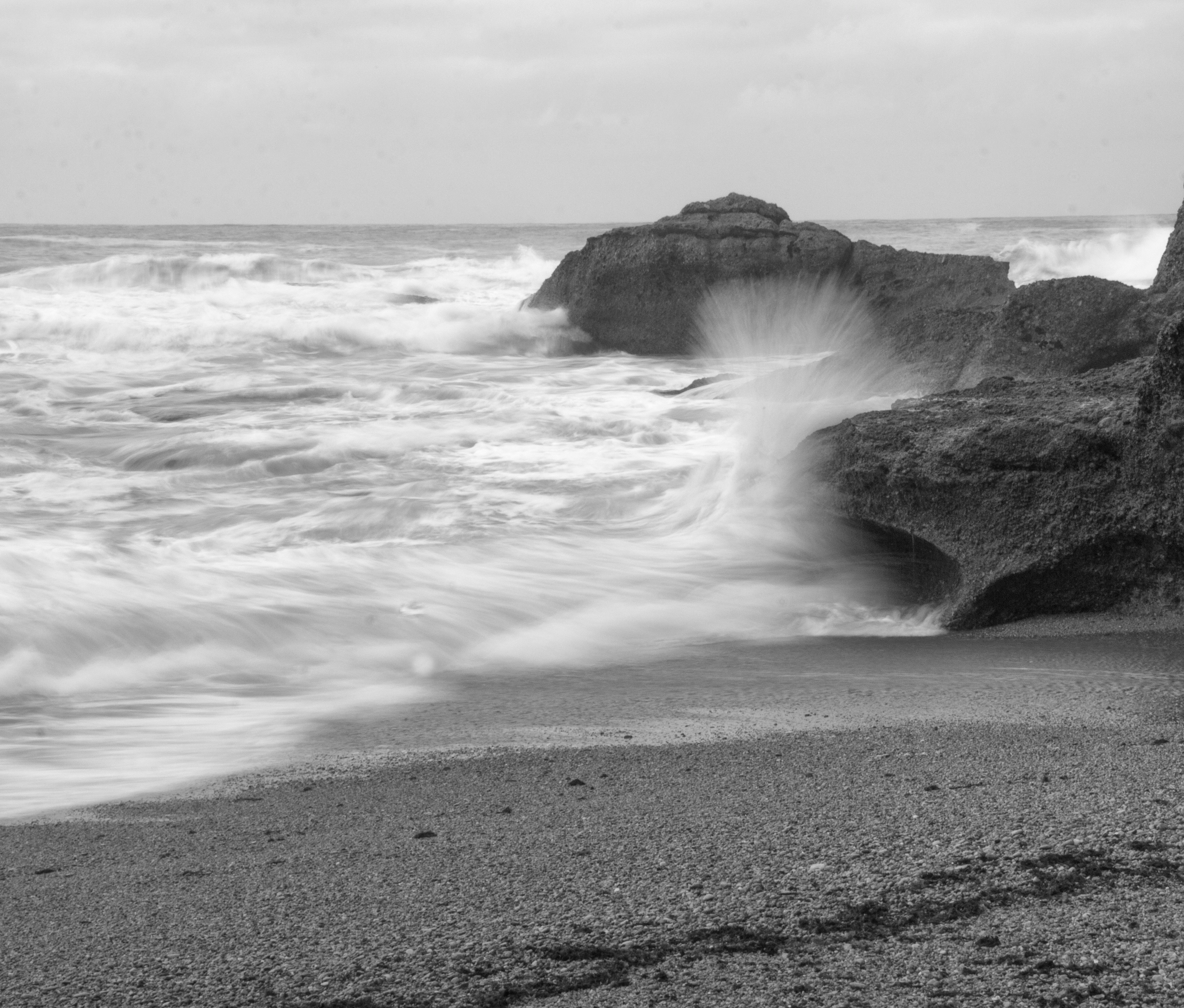 grayscale photography of sea wave splashing on rock