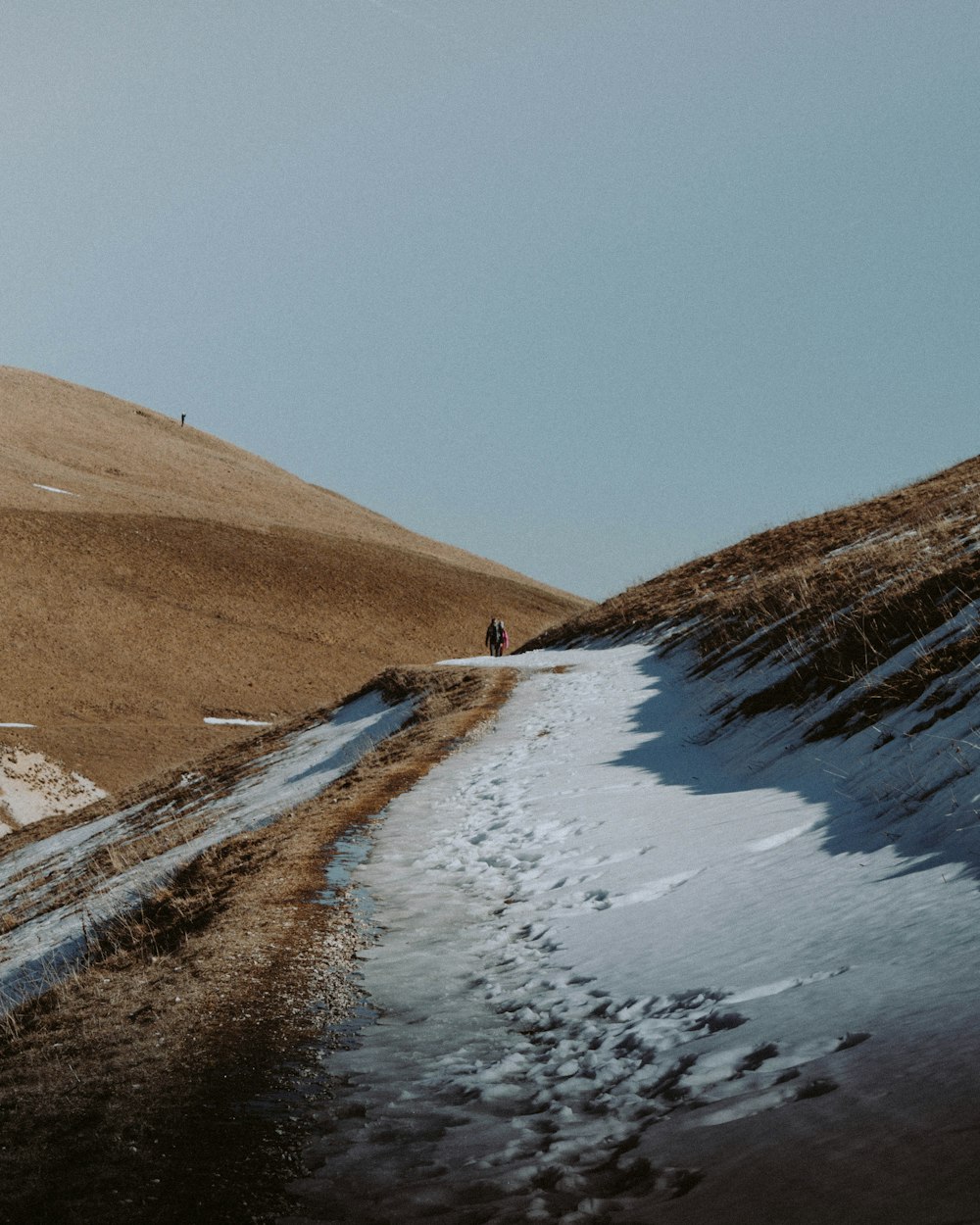 two people walking on snow covered dirt trail