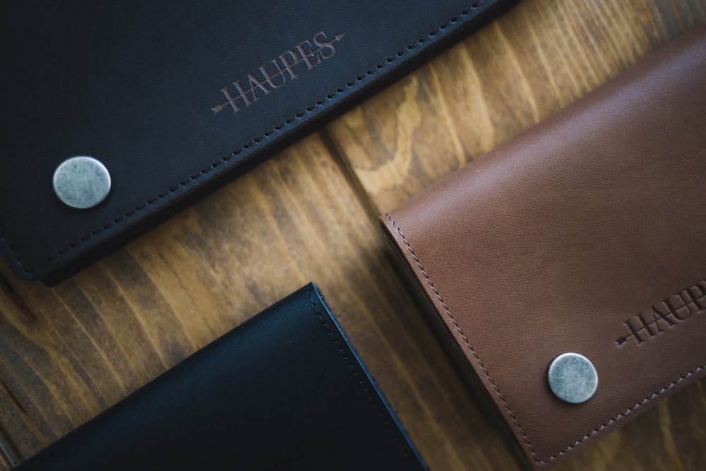 three brown and black Haupes leather wallets