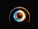A close-up of a gas stove burner with a blue and yellow flame surrounding a dark central structure, set against a black background.
