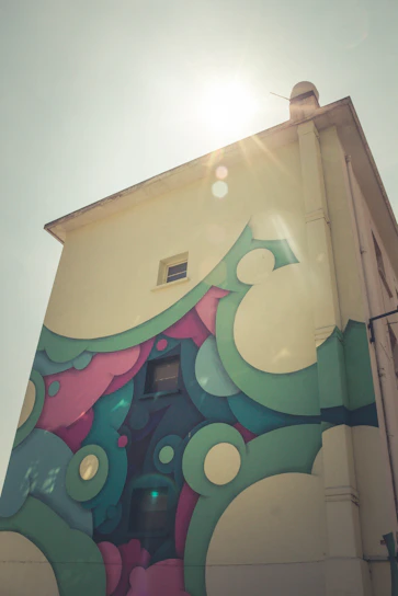 A cheerful artist painting a colorful mural on a storefront window during golden hour.
