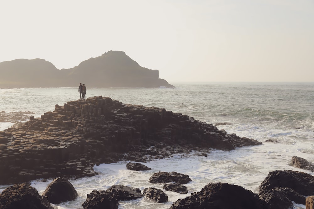 Dos personas de pie frente al mar durante el día