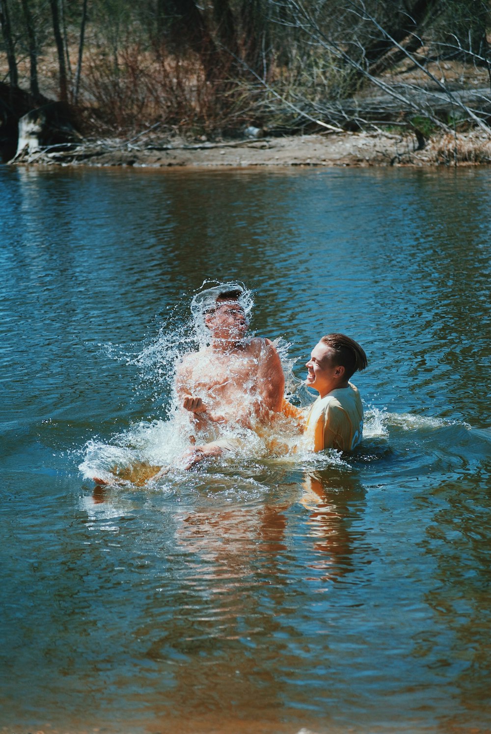 boy and man swimming near tree during daytime