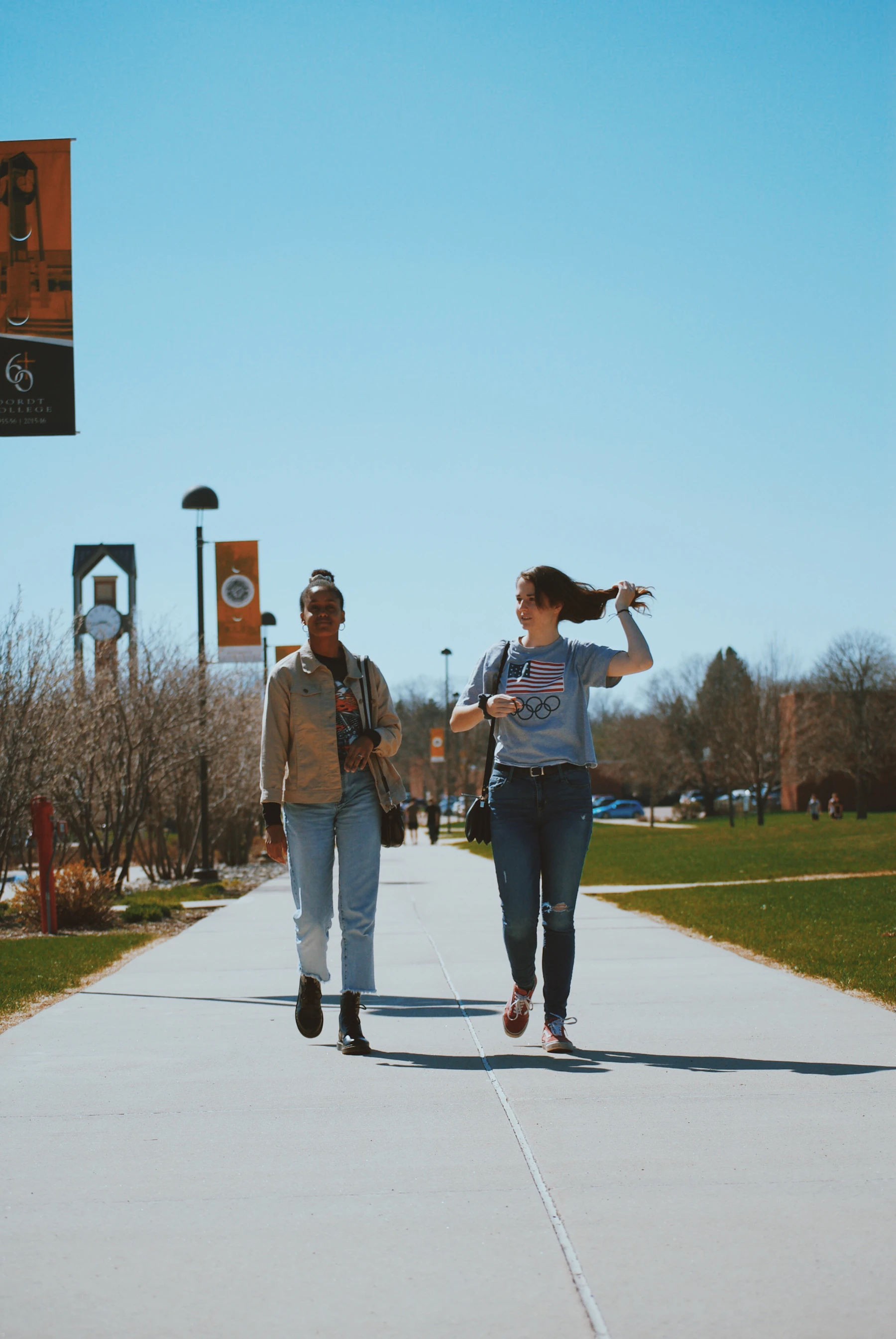 Two people walking across a sunny university campus