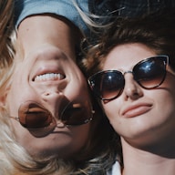 two women wearing sunglasses lying beside each other