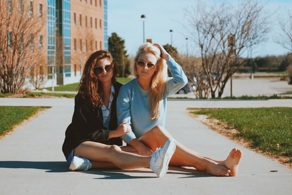 two women sitting close to each other on pathway