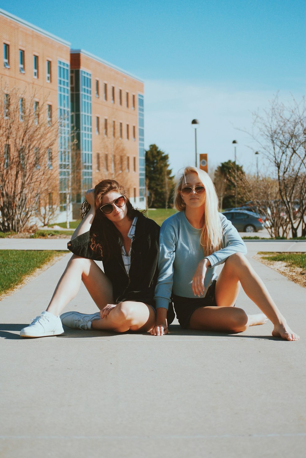 two women sitting on pathway beside each other