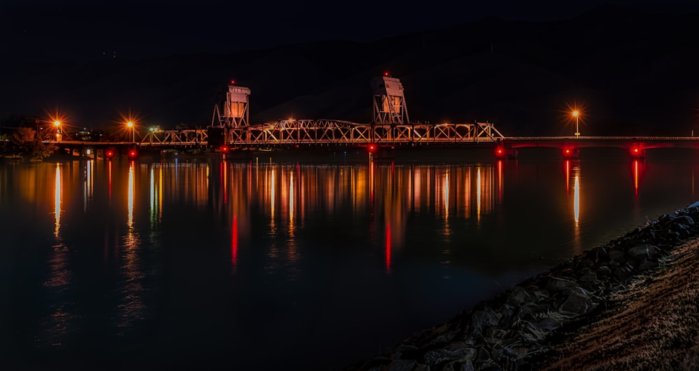 yellow and red lights on bridge reflecting on water at nighttime