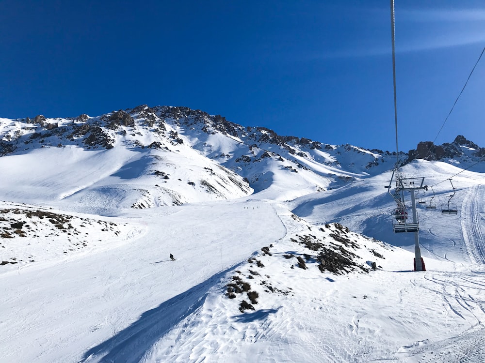 field and mountain covered with snow showing cable car