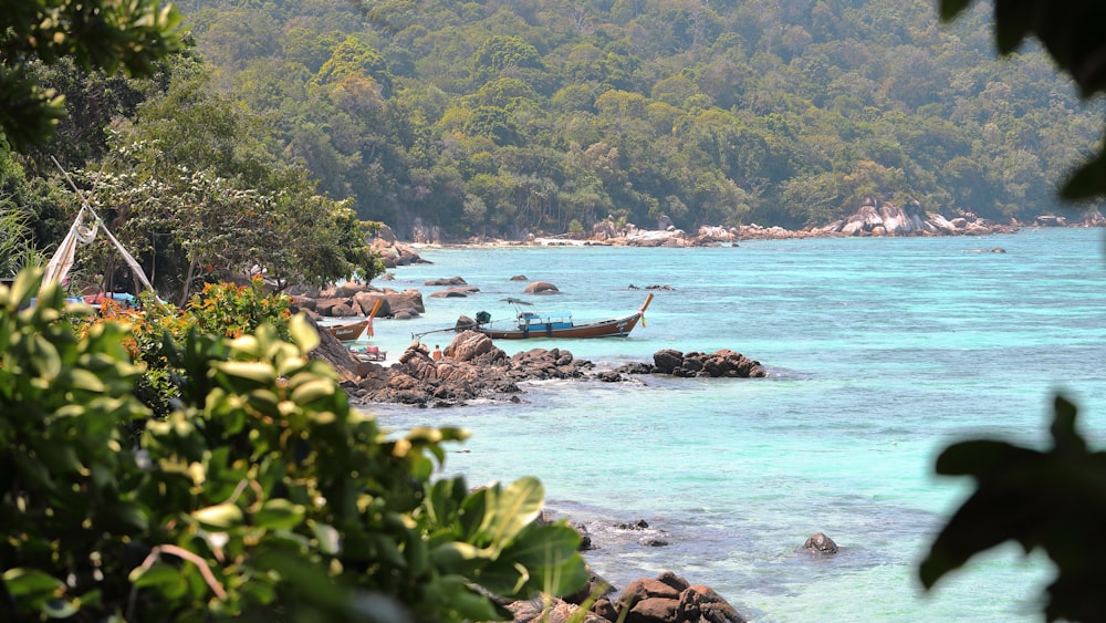 brown boat near rocks viewing sea