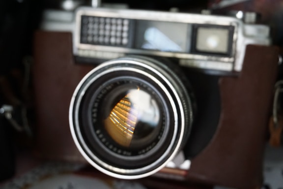A sleek, cinematic close-up of a vintage film camera lens with soft spotlight reflections.