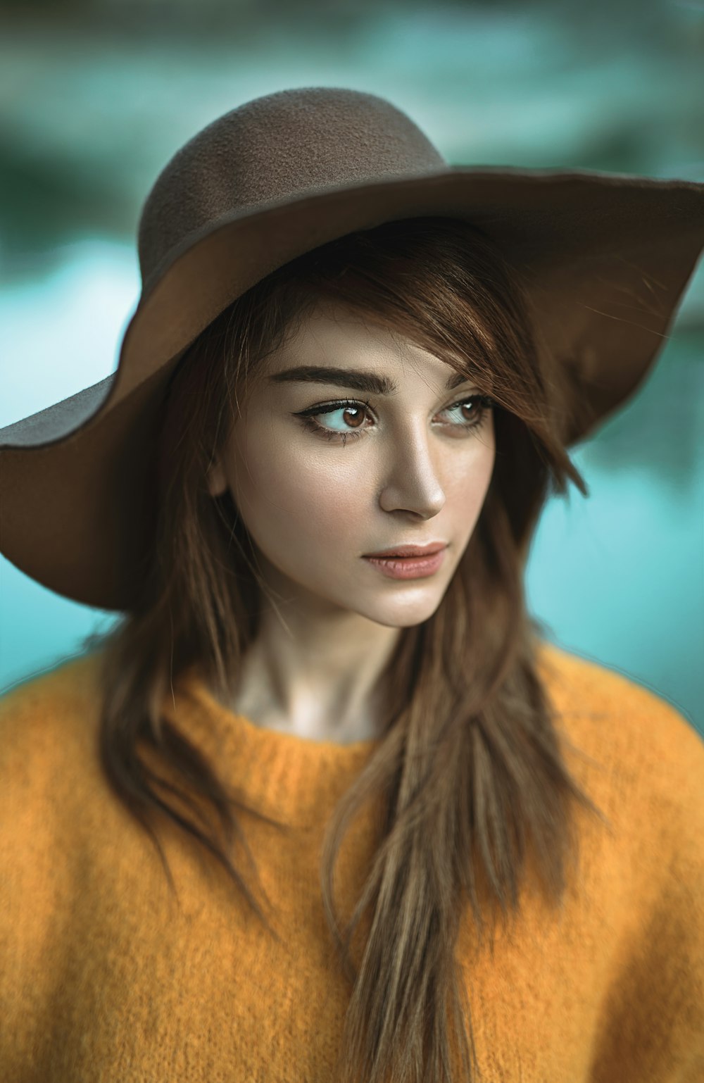 Mujer con suéter amarillo y sombrero marrón mirando su lado derecho