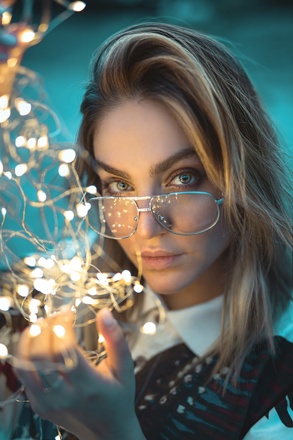 woman wearing eyeglasses holding white string lights