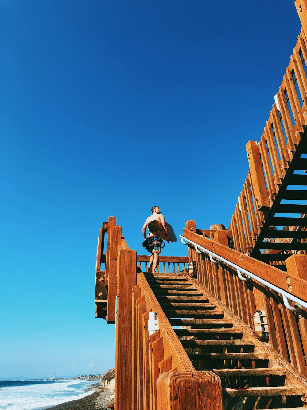 man carrying surfboard climbing on stairs