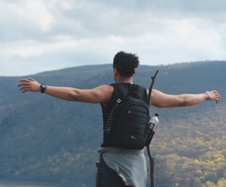 person standing on cliff under white clouds