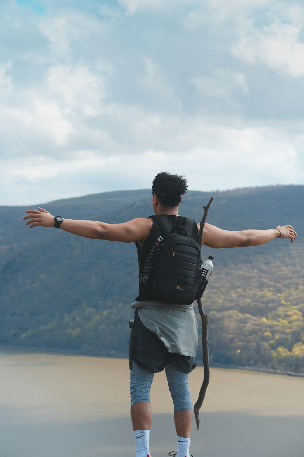 person standing on cliff under white clouds