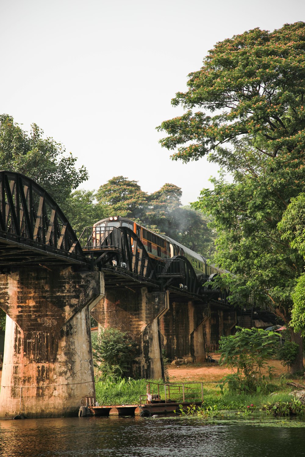 brown concrete bridge between trees under white sky