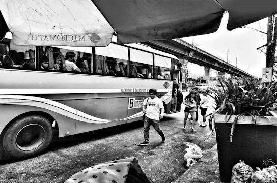City bus stopping at a busy urban intersection with passengers boarding.