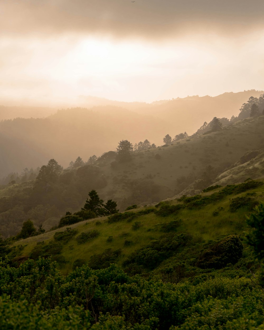 green mountain slope under cloudy sky during daytime