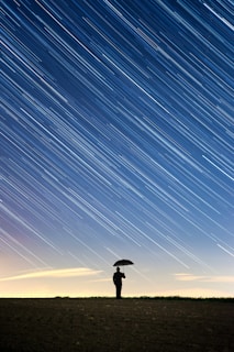 silhouette of standing person holding umbrella