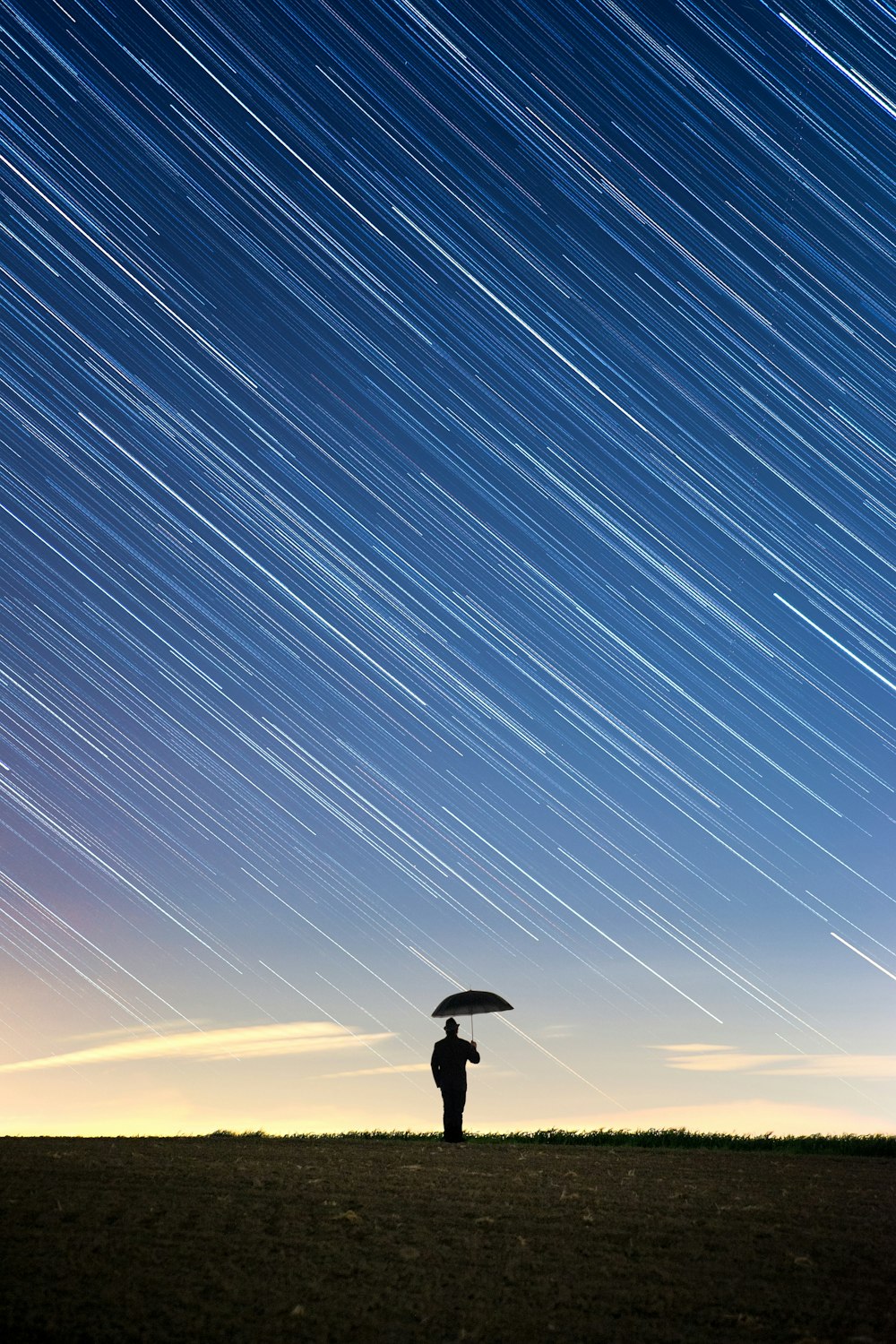 silhouette of standing person holding umbrella