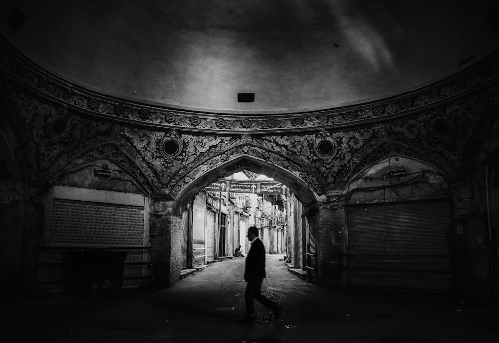 man walking inside gray concrete dome building