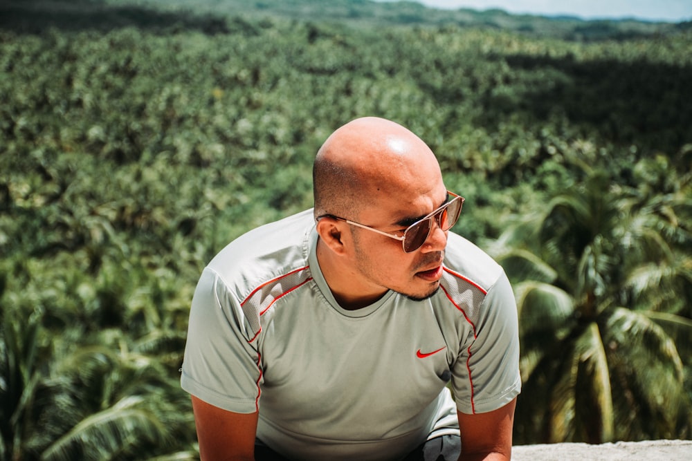 man wearing gray Nike crewneck shrt across green plants