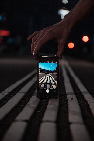 A driver using a smartphone app to report a deer crossing on a rural road at dusk.