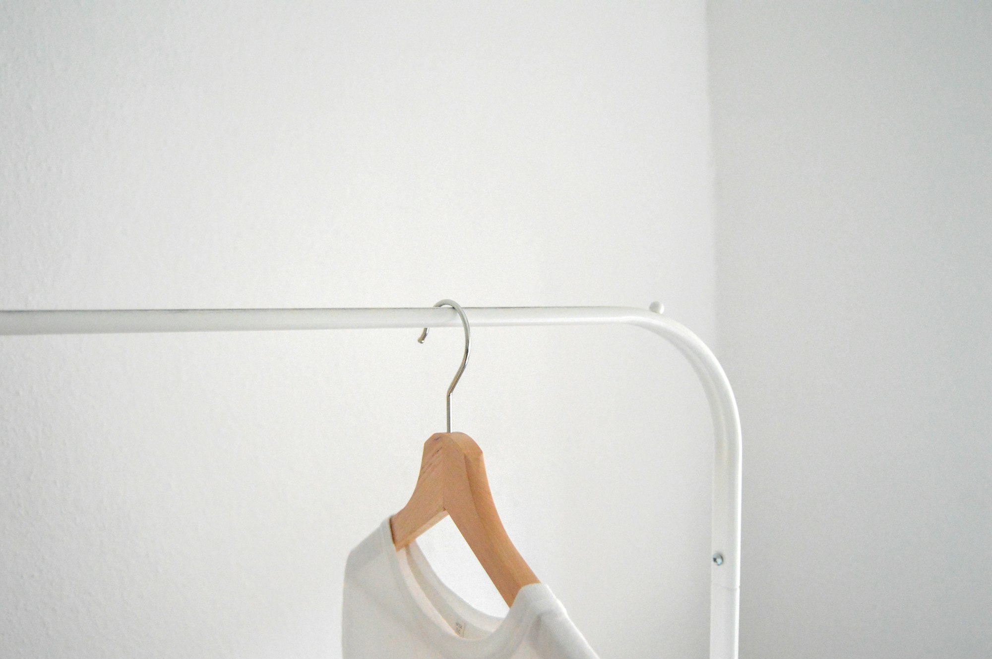 White shirt hanging on clothing rack in front of white wall