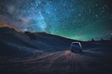 gray vehicle traveling on desert during nighttime