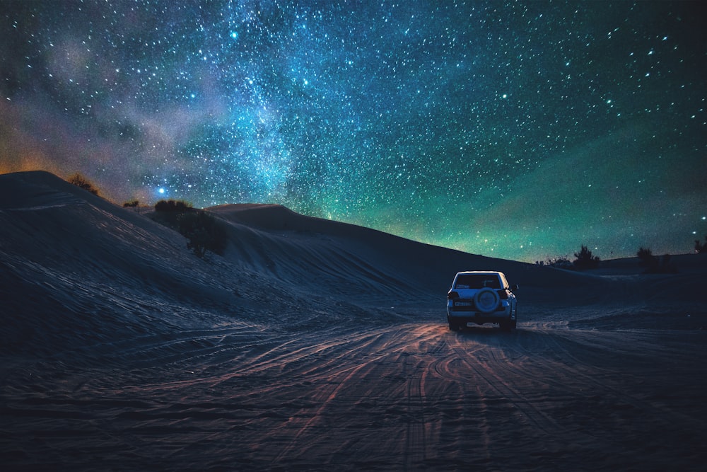 gray vehicle traveling on desert during nighttime