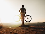 Sunset silhouette of a cyclist on a hill, symbolizing passion and freedom.