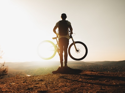 Sunset silhouette of a cyclist on a hill, symbolizing passion and freedom.