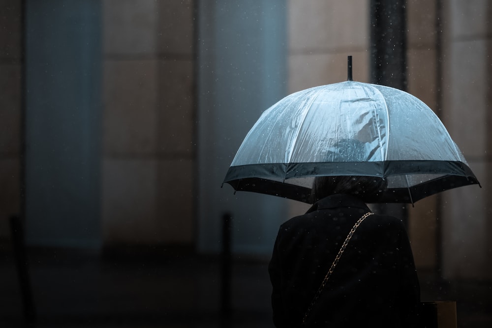 woman wearing black trench coat using white umbrella
