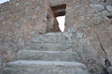 A textured close-up of weathered stone steps leading into an ancient city street.