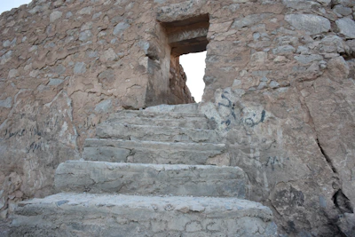A textured close-up of weathered stone steps leading into an ancient city street.