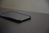 An iPhone resting on a sleek surface, screen showing home automation controls.