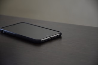 An iPhone resting on a sleek surface, screen showing home automation controls.