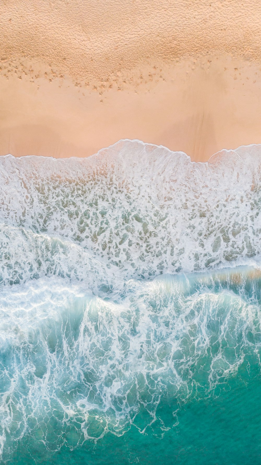 fotografia aerea delle onde che spruzzi sulla spiaggia di sabbia bianca