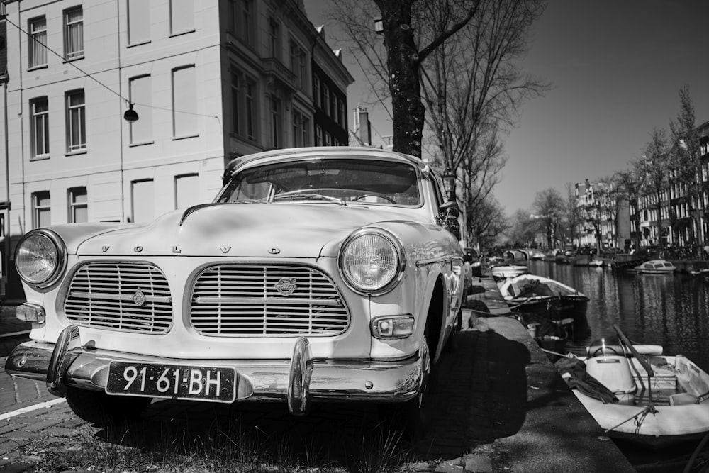 grayscale photography of vehicle beside building and tree\